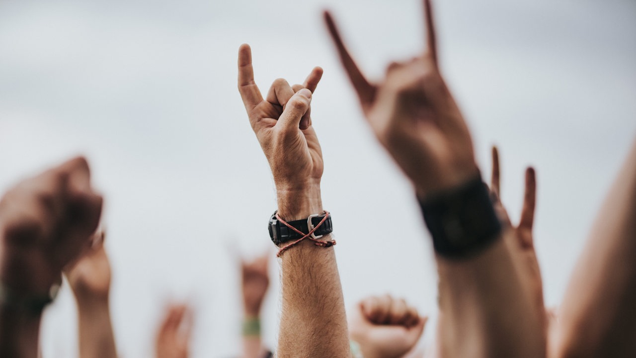 Eine Gruppe von Menschen auf einem Konzert reckt die Hände nach oben