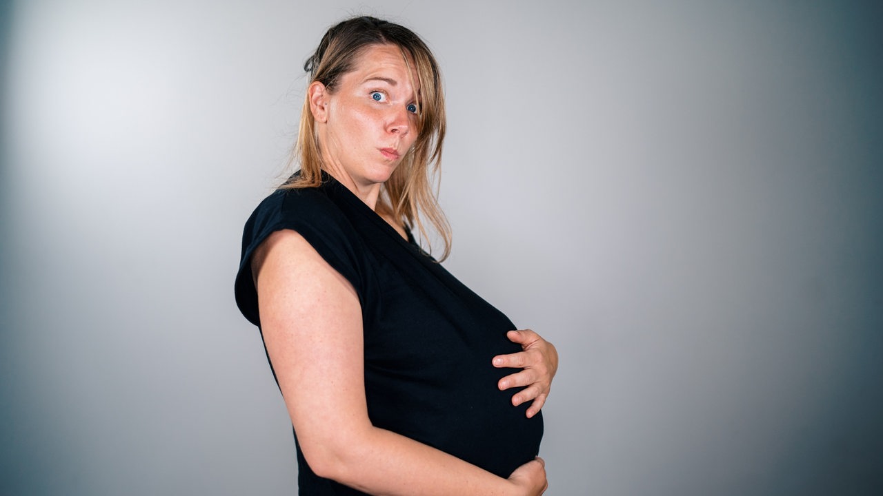 Eine schwangere Frau vor grauem Hintergrund