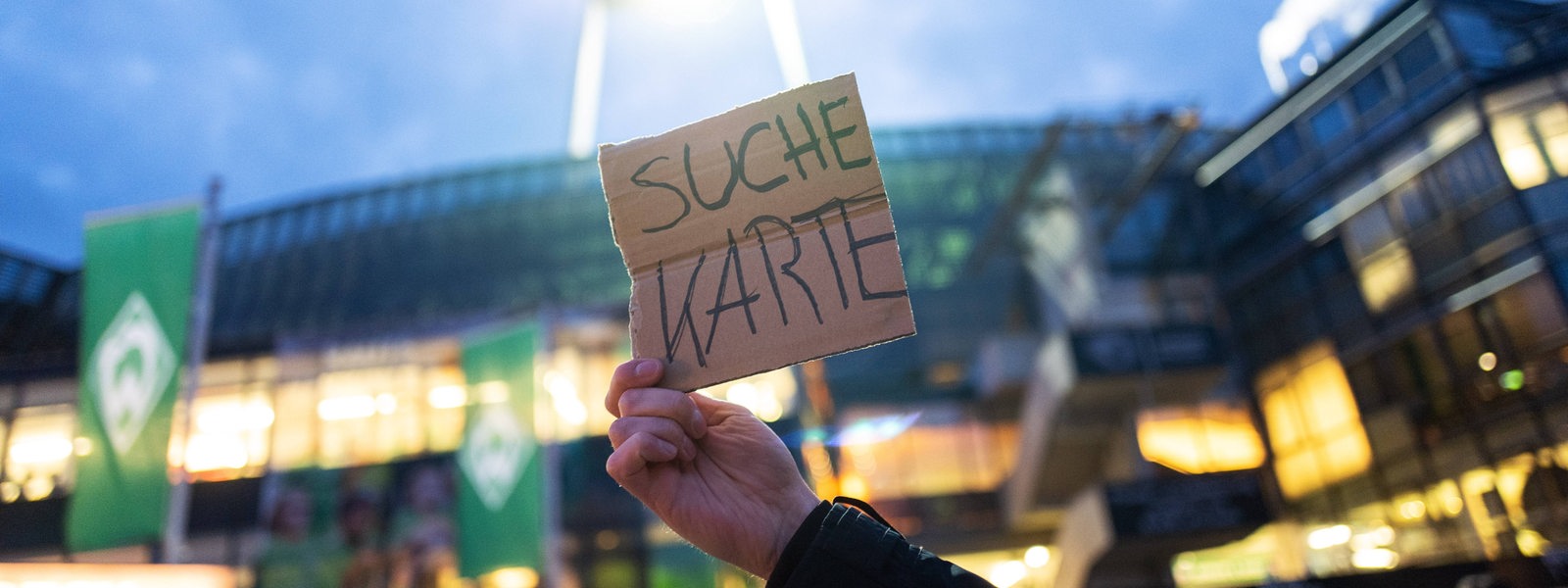 Vor dem Weser-Stadion hält ein Fans ein Pappschild hoch mit der Aufschrift "Suche Karte".