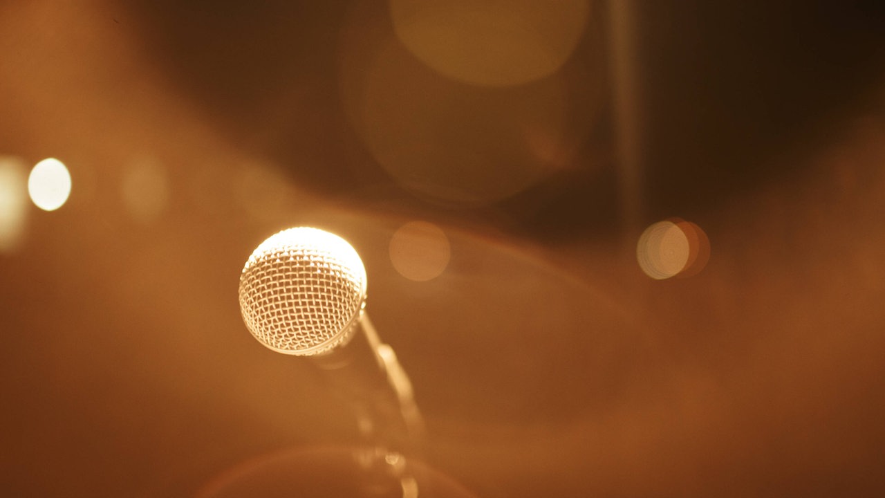 Ein Mikrofon im gelblichen Scheinwerferlicht.