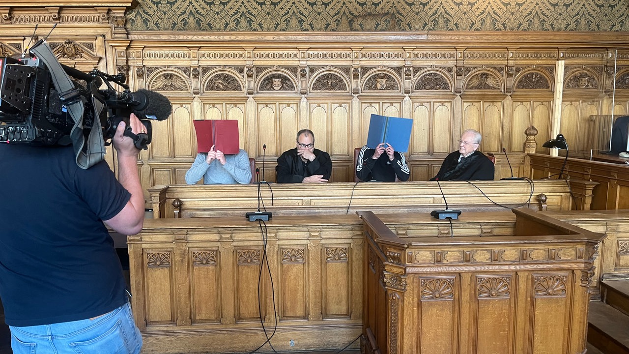Mehrere Männer sitzen im Saal des Bremer Landgerichts auf der Seite der Verteidigung.