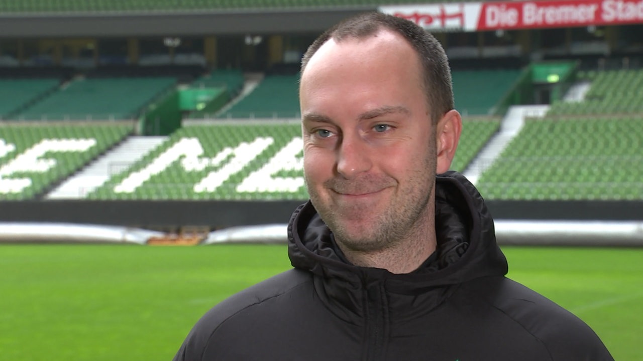 Werder-Trainer Ole Werner lächelt bei einem Interview im leeren Weserstadion.