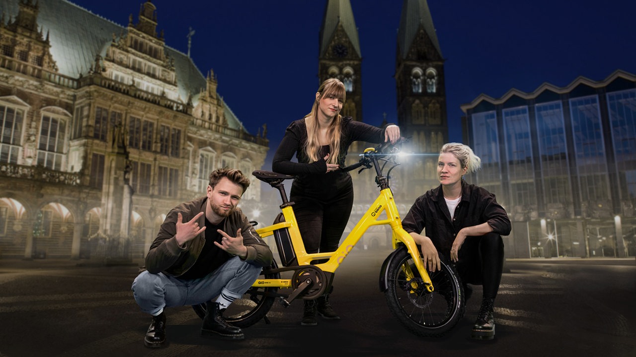 Franzi Pille, Pit Kröger und Tine Kuntze stehen und hocken an einem gelben E-Bike